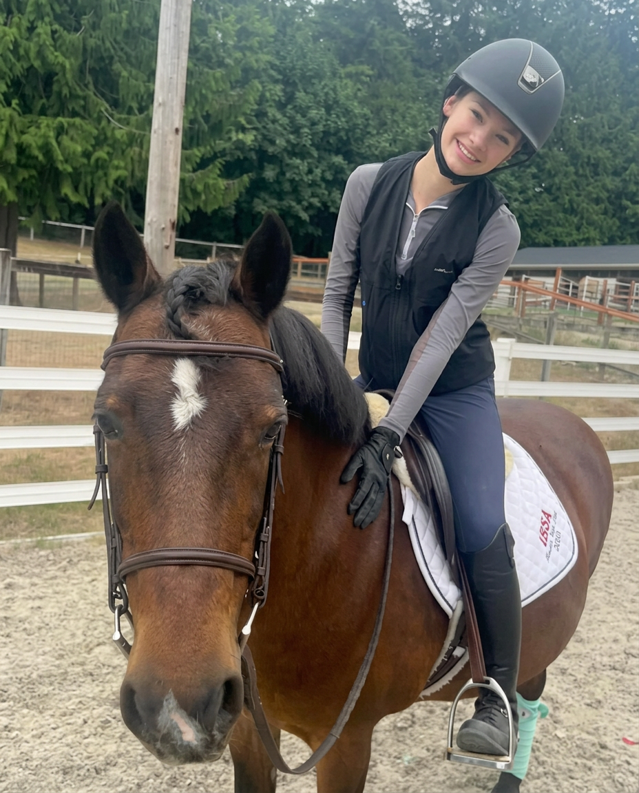 Madison smiling in the saddle on her bay horse in the arena