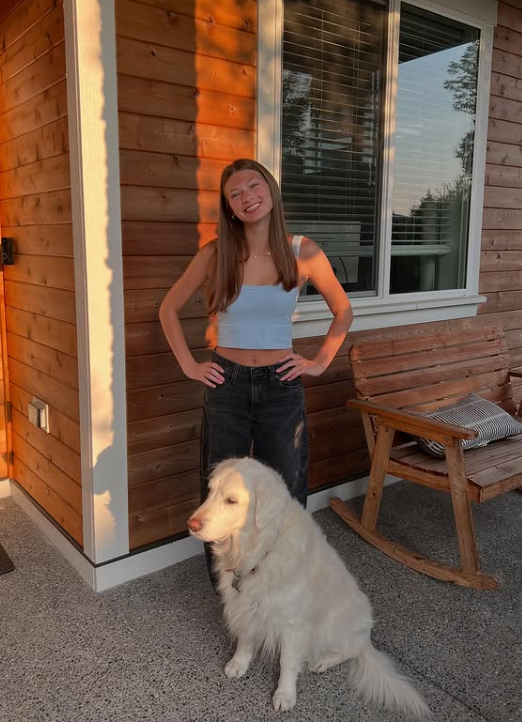 Madison standing with Lily, her white golden retriever, at their Fox Island home