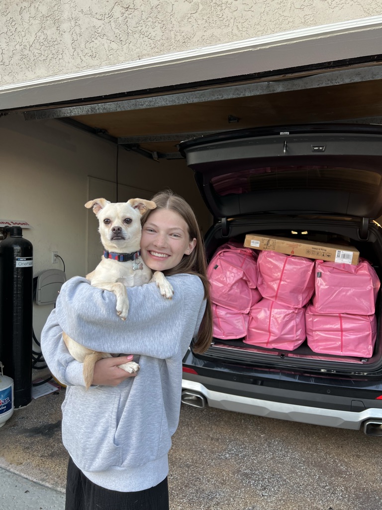 Madison holding a small dog by the car